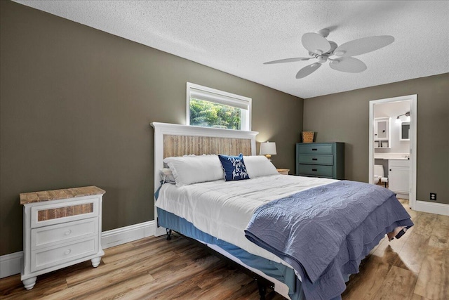 bedroom featuring hardwood / wood-style flooring, ensuite bath, ceiling fan, and a textured ceiling