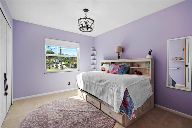 bedroom featuring an inviting chandelier, carpet floors, and a closet