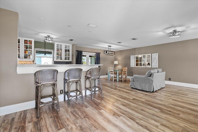 kitchen featuring pendant lighting, a kitchen bar, kitchen peninsula, and light wood-type flooring