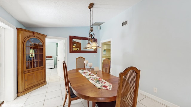 dining area featuring light tile patterned floors, vaulted ceiling, and a textured ceiling