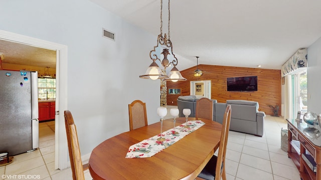 dining area with lofted ceiling, light tile patterned flooring, and wood walls