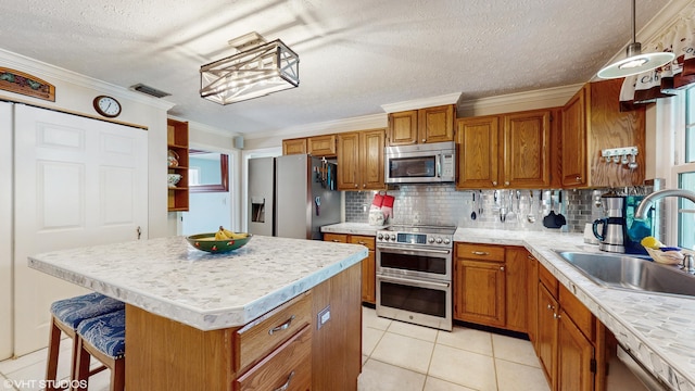 kitchen with sink, decorative light fixtures, a center island, appliances with stainless steel finishes, and backsplash