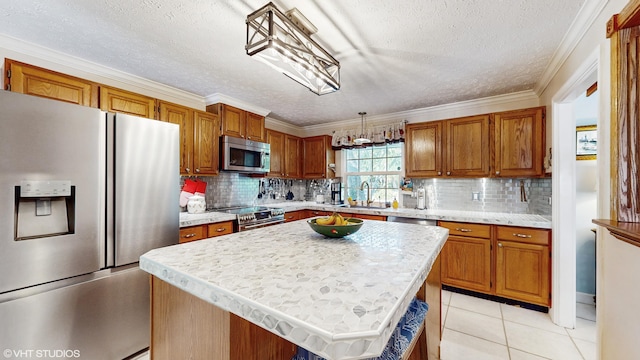 kitchen featuring sink, crown molding, hanging light fixtures, stainless steel appliances, and a kitchen island