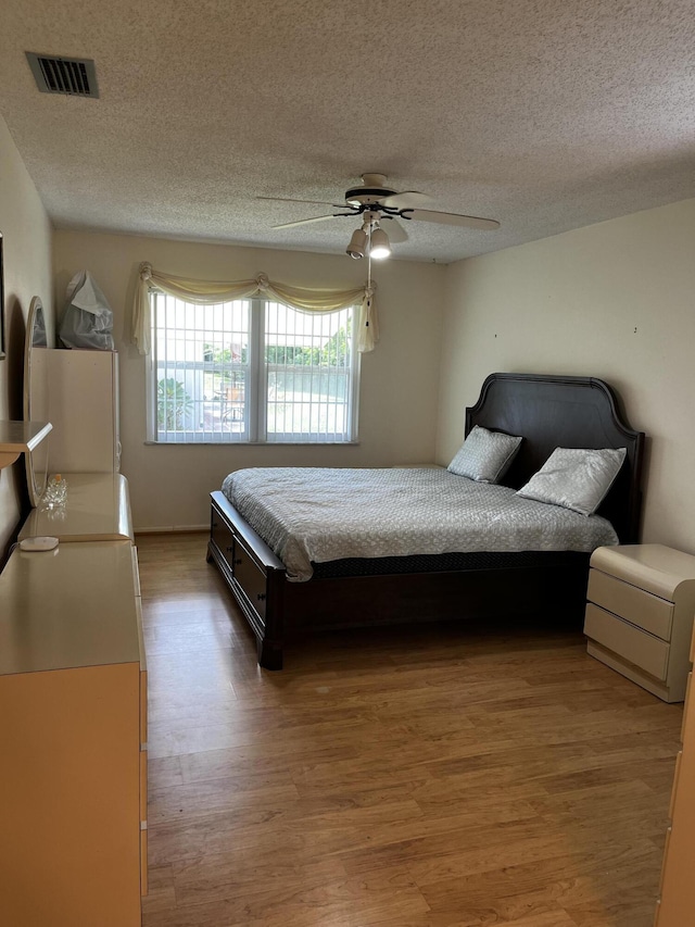 bedroom featuring hardwood / wood-style flooring, ceiling fan, and a textured ceiling