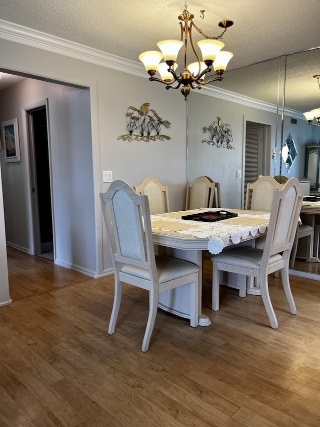 dining space featuring a textured ceiling, ornamental molding, and a chandelier