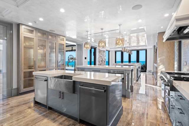 kitchen featuring a tray ceiling, a center island, crown molding, a water view, and hanging light fixtures