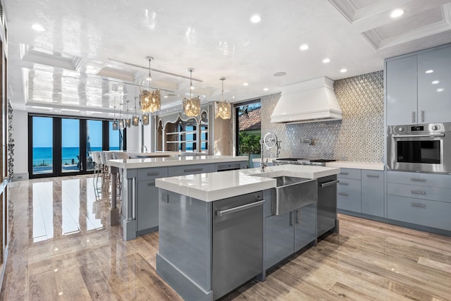 kitchen with ornamental molding, a tray ceiling, a breakfast bar, and decorative light fixtures