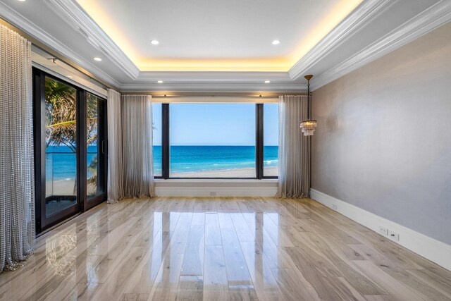 spare room featuring a raised ceiling, wood finished floors, crown molding, a chandelier, and recessed lighting