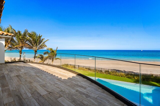 water view featuring fence and a beach view