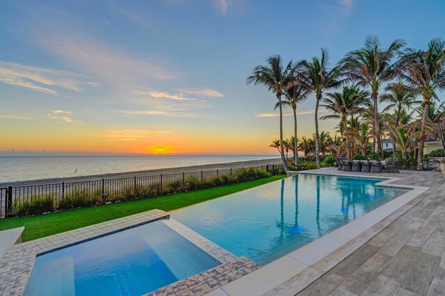 view of pool featuring a fenced in pool, a water view, and a hot tub