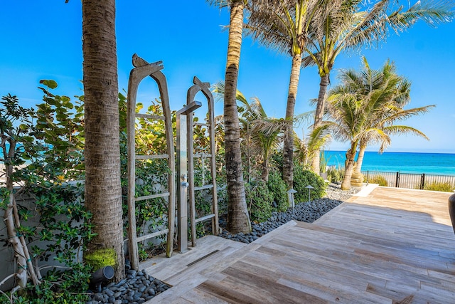 deck featuring a water view, fence, and a view of the beach