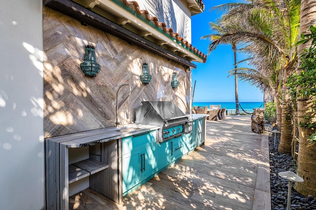 view of patio / terrace with a water view, a grill, and an outdoor kitchen