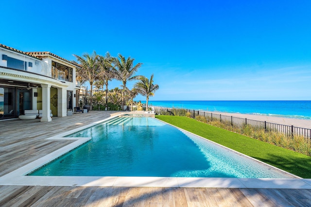 view of pool with a lawn, a fenced in pool, a water view, fence, and a view of the beach