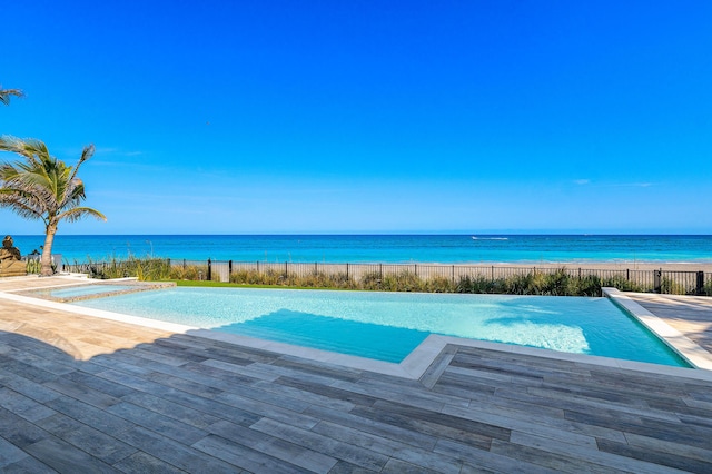 view of pool with a water view, a hot tub, and a fenced in pool