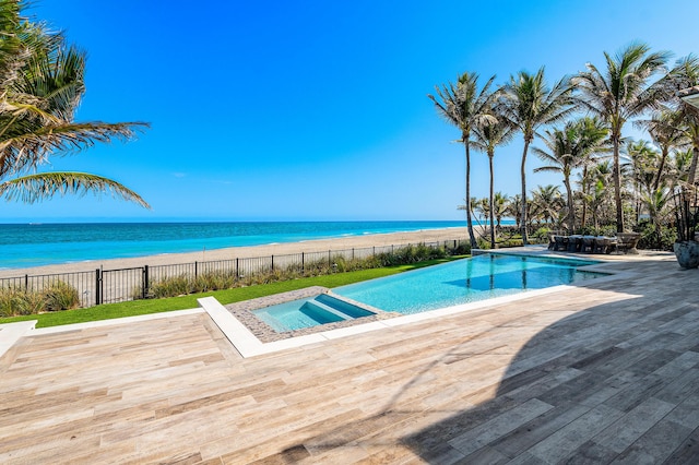 view of swimming pool featuring a water view, fence, a fenced in pool, and an in ground hot tub