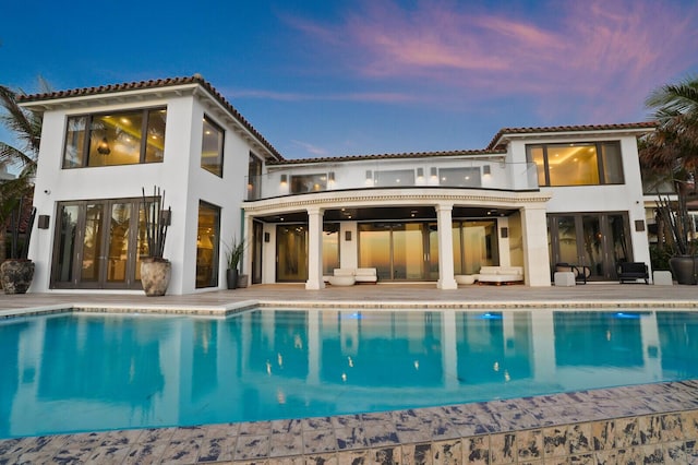 back of house with a patio, a fenced backyard, a pool with connected hot tub, and stucco siding