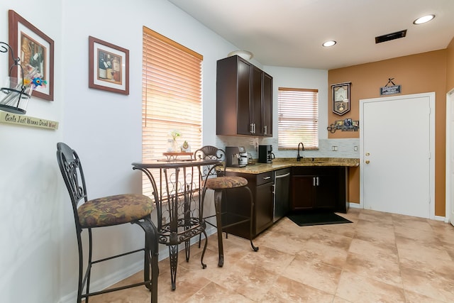 kitchen featuring dishwasher, dark brown cabinets, sink, and light stone counters