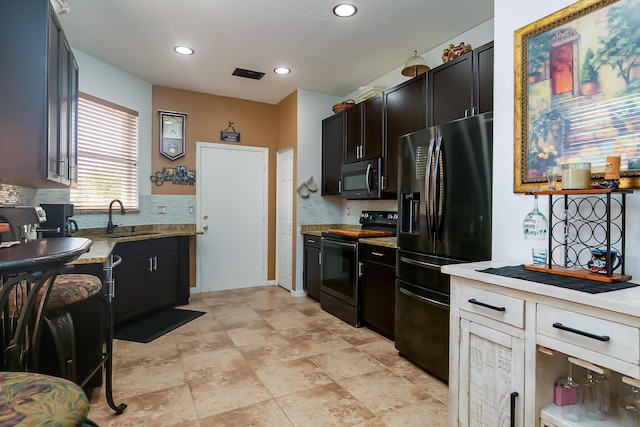 kitchen with light stone countertops, sink, backsplash, and black appliances