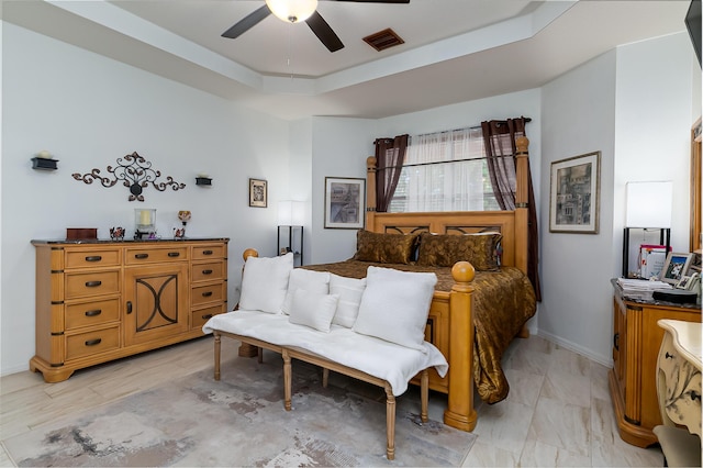 bedroom with ceiling fan and a tray ceiling