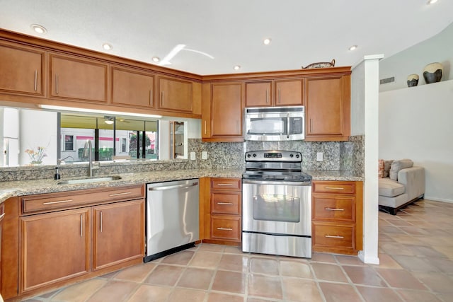 kitchen with sink, light tile patterned floors, appliances with stainless steel finishes, light stone counters, and tasteful backsplash