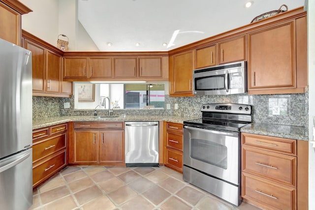 kitchen featuring sink, decorative backsplash, light tile patterned floors, light stone counters, and stainless steel appliances