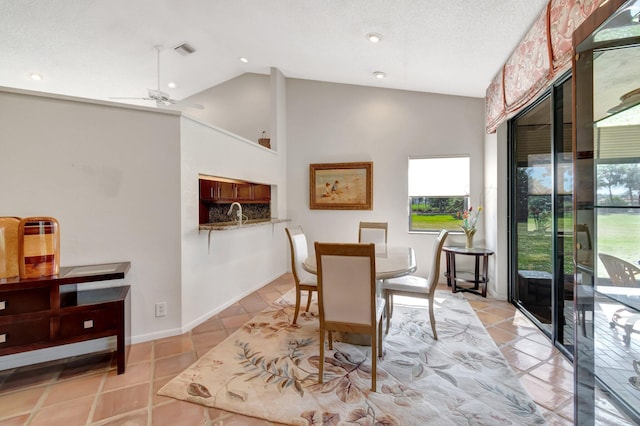 dining area with light tile patterned flooring, vaulted ceiling, and a textured ceiling