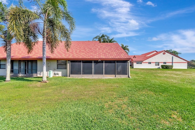 back of property with a sunroom and a lawn