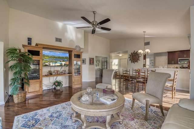 living room featuring high vaulted ceiling, dark hardwood / wood-style flooring, ceiling fan with notable chandelier, and a textured ceiling