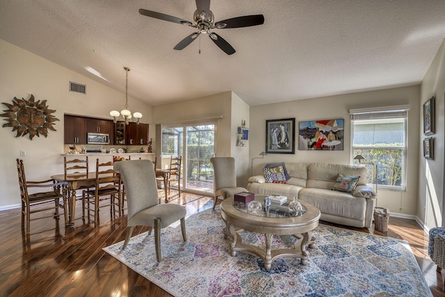 living room featuring lofted ceiling, dark wood-type flooring, ceiling fan with notable chandelier, and a textured ceiling