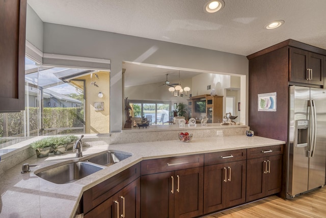 kitchen with sink, light stone counters, stainless steel fridge with ice dispenser, dark brown cabinets, and light hardwood / wood-style flooring