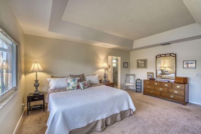 carpeted bedroom with a textured ceiling and a tray ceiling