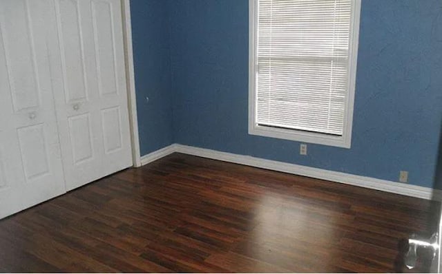 unfurnished bedroom featuring dark wood-type flooring and a closet