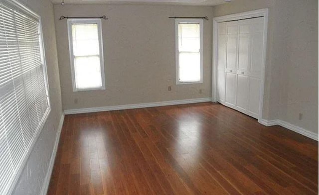 unfurnished bedroom with dark hardwood / wood-style flooring and a closet