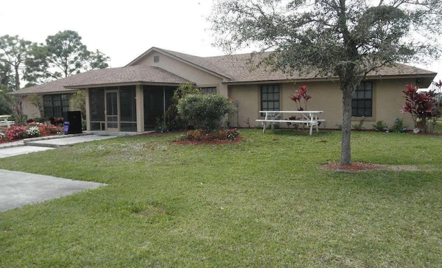 rear view of property with a lawn and a sunroom