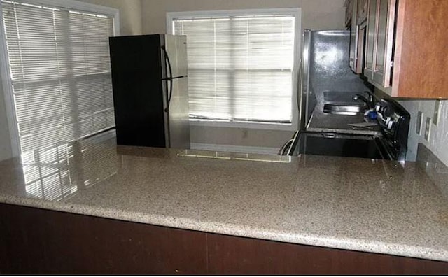 kitchen featuring black refrigerator, sink, stainless steel refrigerator, and range