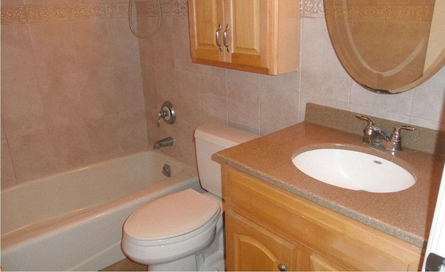 full bathroom with vanity, toilet, tiled shower / bath combo, and tile walls