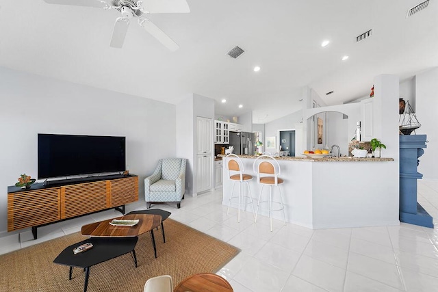 living room with lofted ceiling, light tile patterned floors, and ceiling fan