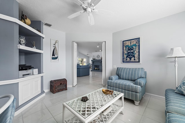 living room featuring light tile patterned floors, a textured ceiling, and ceiling fan