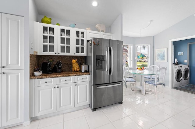 kitchen featuring white cabinetry, stainless steel fridge with ice dispenser, dark stone countertops, independent washer and dryer, and backsplash