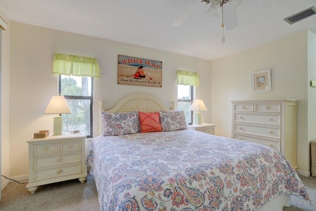 bedroom featuring ceiling fan, light colored carpet, and a textured ceiling