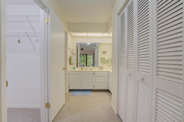 corridor featuring sink and light carpet