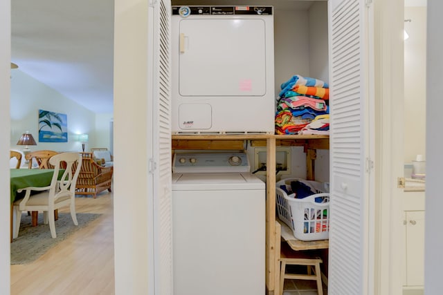 clothes washing area with stacked washer and clothes dryer and light hardwood / wood-style floors