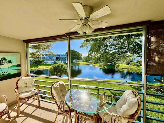 sunroom featuring ceiling fan and a water view