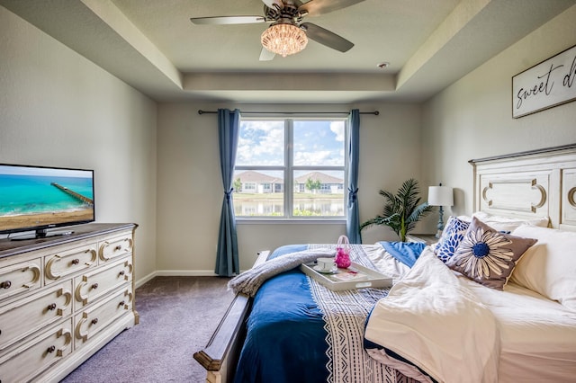 carpeted bedroom featuring a tray ceiling and ceiling fan