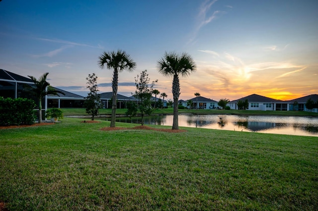 yard at dusk featuring a water view