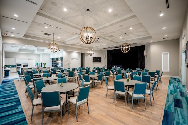 dining area with a raised ceiling, crown molding, a chandelier, and light wood-type flooring