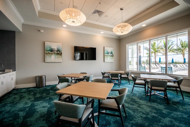 carpeted dining area featuring ornamental molding, a raised ceiling, and sink