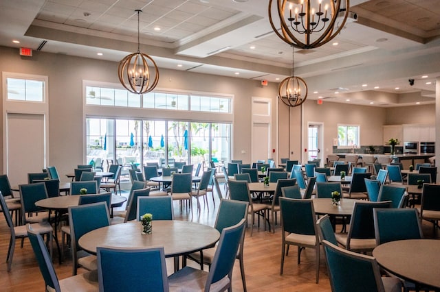 dining room with an inviting chandelier, a towering ceiling, crown molding, and light wood-type flooring