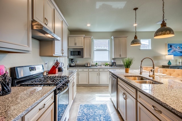 kitchen with stainless steel appliances, sink, decorative light fixtures, a healthy amount of sunlight, and light stone countertops