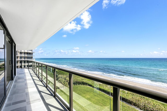 balcony with a water view and a view of the beach